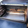 The inside of a grill with a metal drip pan. Produktbild-Vorschau