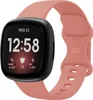A Fitbit Versa 4 smartwatch with a pink silicone band is shown against a white background. Produktbild-Vorschau