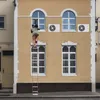 A person on a ladder is working on a window of a building. Voir les images du produit
