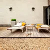 A relaxing outdoor patio scene with lounge chairs, a small table, and decorative elements. Anteprima dell’immagine prodotto