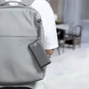 A person wearing a white t-shirt and a grey backpack with a black power bank attached to it. Anteprima dell’immagine prodotto