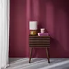 A bedside table with a lamp and books against a pink wall. Produktbild-Vorschau