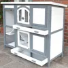A multi-level wooden hutch for rabbits or other small animals, shown outdoors on a stone patio. Produktbild-Vorschau