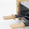 Close-up of a raclette grill with wooden spatulas extended. Produktbild-Vorschau