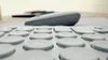 A close-up, low-angle shot of a white keyboard with round keys and a gray mouse in the background. Produktbild-Vorschau