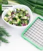 A bowl of chopped salad next to a green vegetable chopper attachment. Voir les images du produit