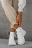 A person wearing beige cargo pants and white high-top sneakers, with gold jewelry on their hand. Produktbild-Vorschau