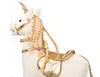 A close-up side view of a white plush unicorn rocking horse with gold accents. Podgląd zdjęcia produktu