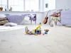 A child's bedroom with a bed, dresser, and a guitar, featuring a LEGO Friends pool party playset on the floor. Produktbild-Vorschau