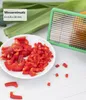 A close-up of chopped red bell peppers on a white plate, next to a green vegetable dicer and some leeks in the background. Voir les images du produit