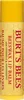 A close-up, vertical shot of a Burt's Bees Beeswax Lip Balm tube against a light yellow, honeycomb-patterned background. Produktbild-Vorschau