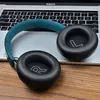 A pair of black headphones with a teal headband rests on a laptop keyboard. Podgląd zdjęcia produktu