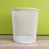 A white mesh waste bin sits on a wooden floor against a bright green wall. Produktbild-Vorschau