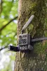 A trail camera is mounted on a tree in a forest. Náhled obrázku produktu