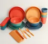 A collection of camping tableware, including plates, bowls, cups, and cutlery, arranged on a white surface. Produktbild-Vorschau