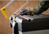A gloved hand is cutting a copper pipe with a hacksaw on top of a toolbox. Voir les images du produit