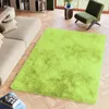A lime green rug is placed on a wooden floor in a living room setting, next to a beige sofa and a green armchair. Voir les images du produit