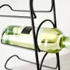 A close-up shot of a black metal wine rack holding a bottle of white wine. Anteprima dell’immagine prodotto