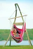 A woman is relaxing in a colorful hammock chair on a grassy area near a body of water. Anteprima dell’immagine prodotto