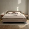 A modern, upholstered bed with a padded headboard is set up in a bedroom with soft lighting. Produktbild-Vorschau
