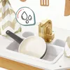 A close-up of a toy kitchen sink with a pan in it, a golden faucet with water running, and a decorative cloth in the background. There is also an overlay graphic of water drops. Podgląd zdjęcia produktu
