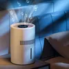 A white air purifier/humidifier sits on a nightstand next to a bed in a dimly lit room, with blue light effects and bubbles emanating from the top. Náhled obrázku produktu