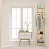 A gold garment rack with clothes and accessories displayed in a room with a window. Podgląd zdjęcia produktu