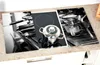 A glass cutting board with a black and white image of an espresso machine and a pot on a stovetop, placed on a kitchen counter. Podgląd zdjęcia produktu