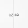 A close-up view of two silver cabinet knobs on a white surface, likely cabinet doors. Náhled obrázku produktu