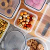 A collection of food storage containers filled with various snacks and cookies, arranged on a wooden surface. Náhled obrázku produktu