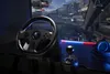 A gaming setup with a racing wheel, shifter, and headphones, connected to a screen displaying a racing game. Náhľad obrázku produktu