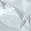 A close-up view of white fabric, likely bedding, with soft folds and shadows. Produktbild-Vorschau