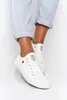 A person wearing white sneakers and light blue jeans. Podgląd zdjęcia produktu