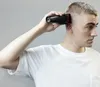 A man is using a hair clipper on his own head. Podgląd zdjęcia produktu