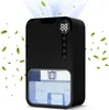 A black electric dehumidifier with a digital display and water tank is shown against a white background, with green leaves floating around it. Produktbild-Vorschau