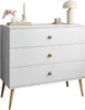 A white dresser with three drawers and wooden legs, decorated with a lamp, candles, and flowers on top. Produktbild-Vorschau