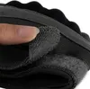 A close-up view of a person's finger touching the velcro closure of a black tactical glove. Produktbild-Vorschau