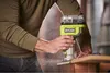 A person is using a Ryobi cordless router to shape a piece of wood, creating sawdust. Anteprima dell’immagine prodotto