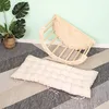 A wooden climbing arch and a cushion are placed on a rug in front of a light green wall. Podgląd zdjęcia produktu