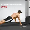 A man performing a push-up exercise on a mat, with a weight machine in the background. Náhľad obrázku produktu