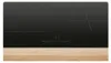A black induction cooktop is shown from a top-down perspective, resting on a light wooden surface. Produktbild-Vorschau