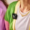 A close-up shot of a person wearing a green cardigan and a gold necklace, with a small black wireless microphone clipped to the cardigan. Anteprima dell’immagine prodotto