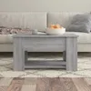A gray wooden coffee table with a bowl of fruit on top, placed on a rug in front of a sofa. Produktbild-Vorschau