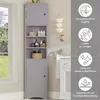 A tall, narrow gray corner cabinet with shelves and doors, placed in a bathroom setting next to a window and a vanity. Informational icons and text are overlaid on the right side of the image. Náhled obrázku produktu