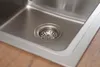 Close-up view of a stainless steel sink drain with a wooden countertop. Produktbild-Vorschau