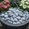 Blaugrau gemaserte Kieselsteine als Abdeckung in einem Pflanzkübel mit bunten Blumen Produktbild-Vorschau