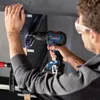 A person is using a Bosch drill to attach something to a cabinet. Produktbild-Vorschau
