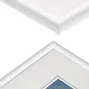 Close-up view of the corners of two white picture frames, one with a white mat and a glimpse of a blue image within. Voir les images du produit