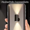 A hand holding a smartphone displaying a wall light. Produktbild-Vorschau