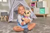 A young girl is sitting on a rug, hugging a stuffed dog in a playroom. Podgląd zdjęcia produktu